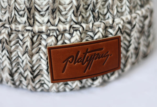 Close up of leather Platypus logo on Oatmeal Knit beanie
