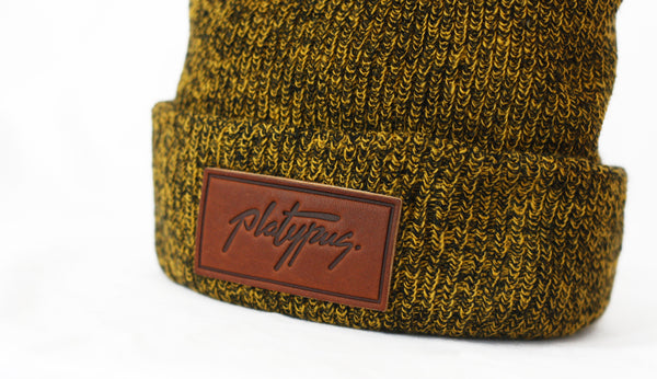 Close up of Platypus leather logo patch on Antique Mustard beanie